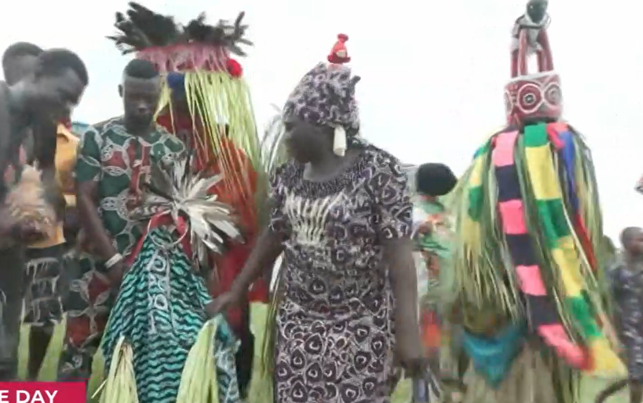 Community members gathered around an Egungun masquerade at a cultural celebration in Takete-Ide