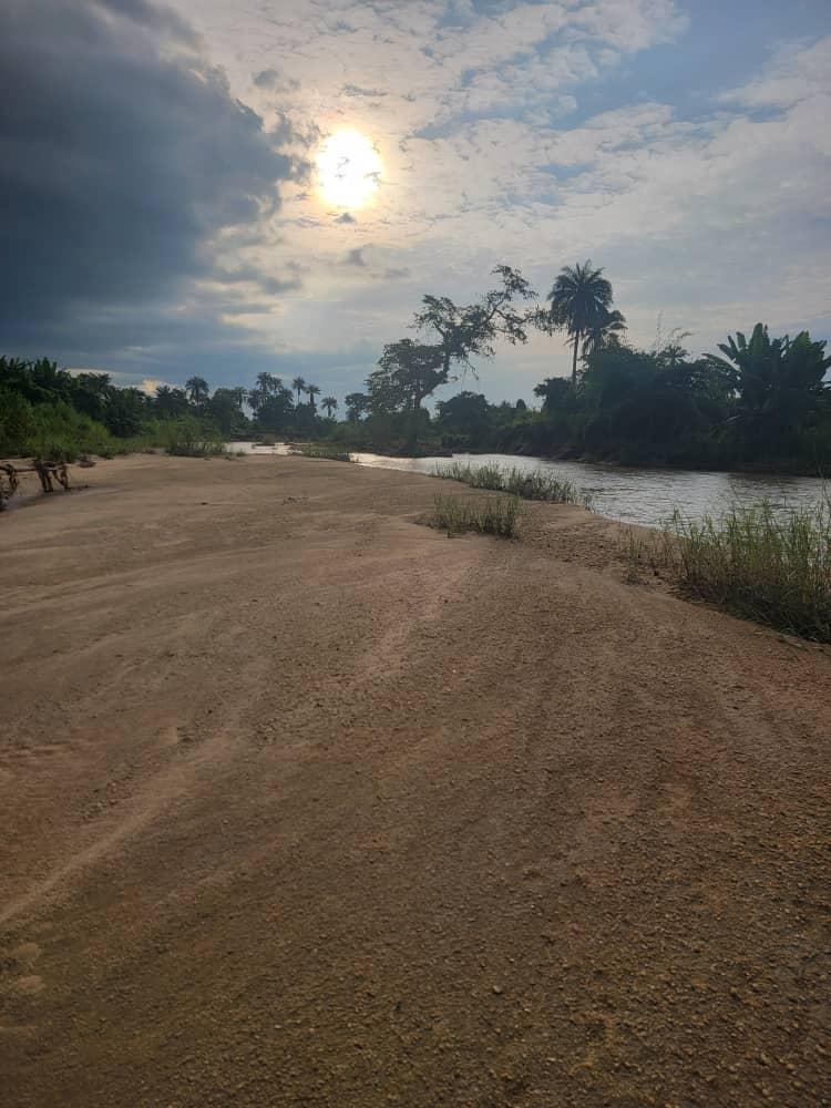 The broad sandy bank of the Eba River with palms along the far bank at dusk